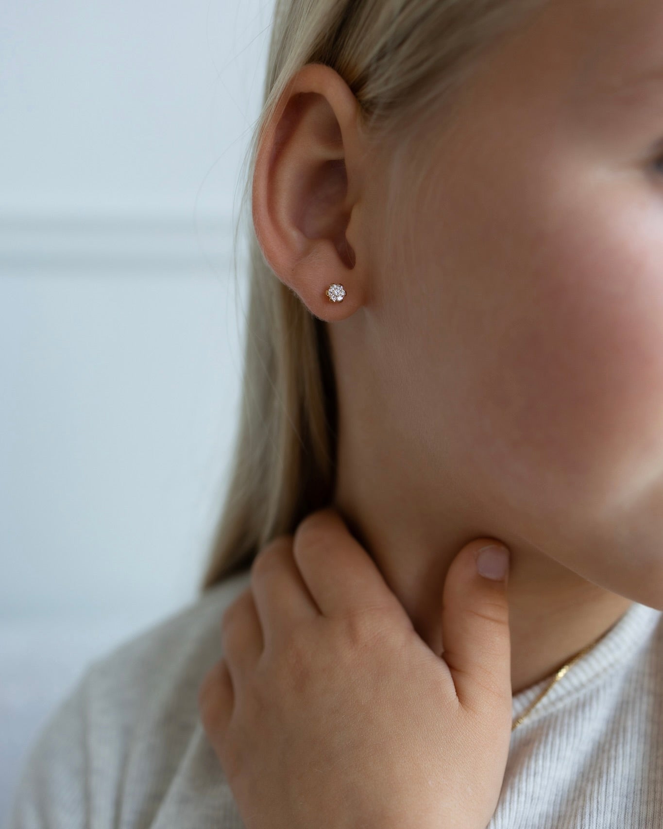 Delicate flower screw-back titanium stud earring worn by a child, secure everyday kids jewelry