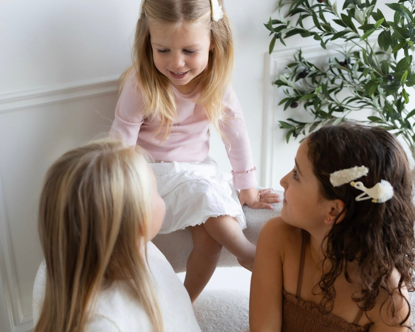 Children wearing delicate jewelry and hair accessories in a soft lifestyle setting